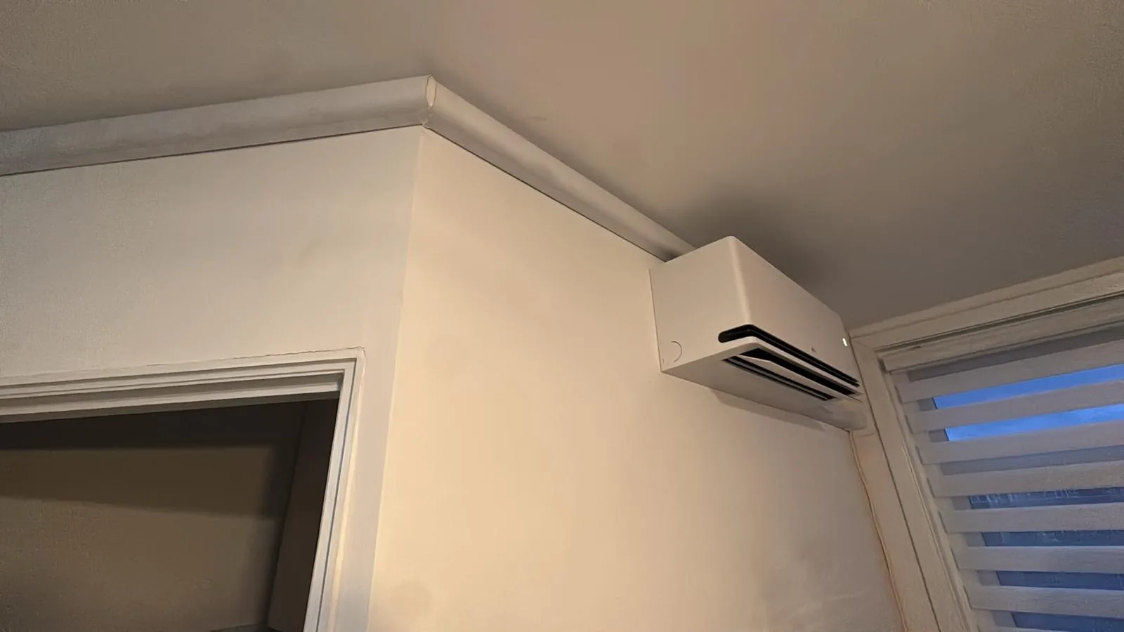 Binnenunit hoog in de hoek met leidingwerk strak langs het plafond