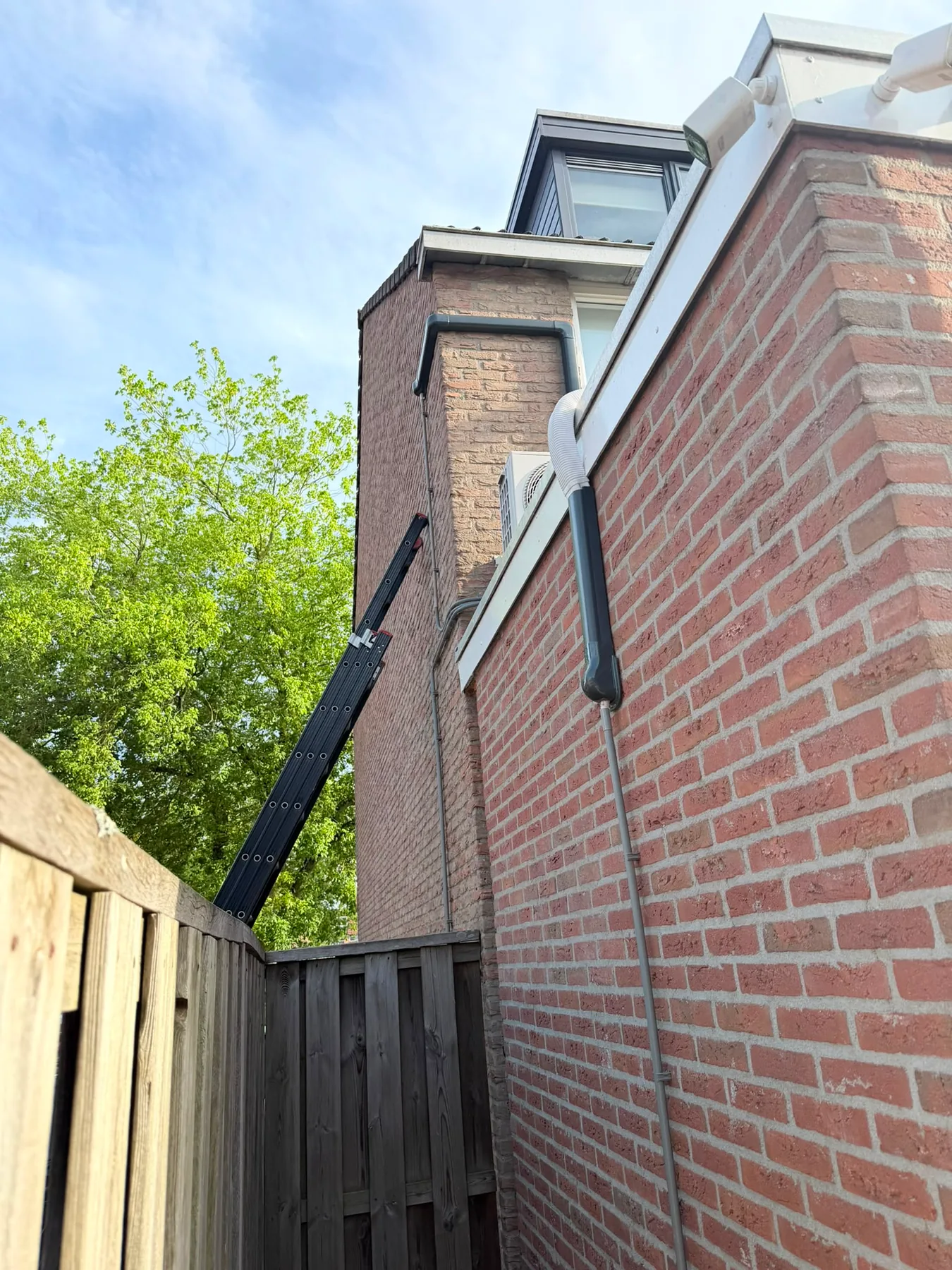 Aircoleidingen in een donkere goot langs een bakstenen gevel