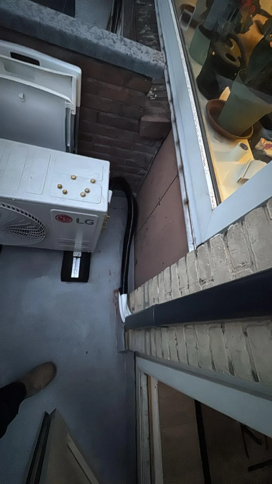 LG buitenunit en leidingroute op een dakrand bij een raam