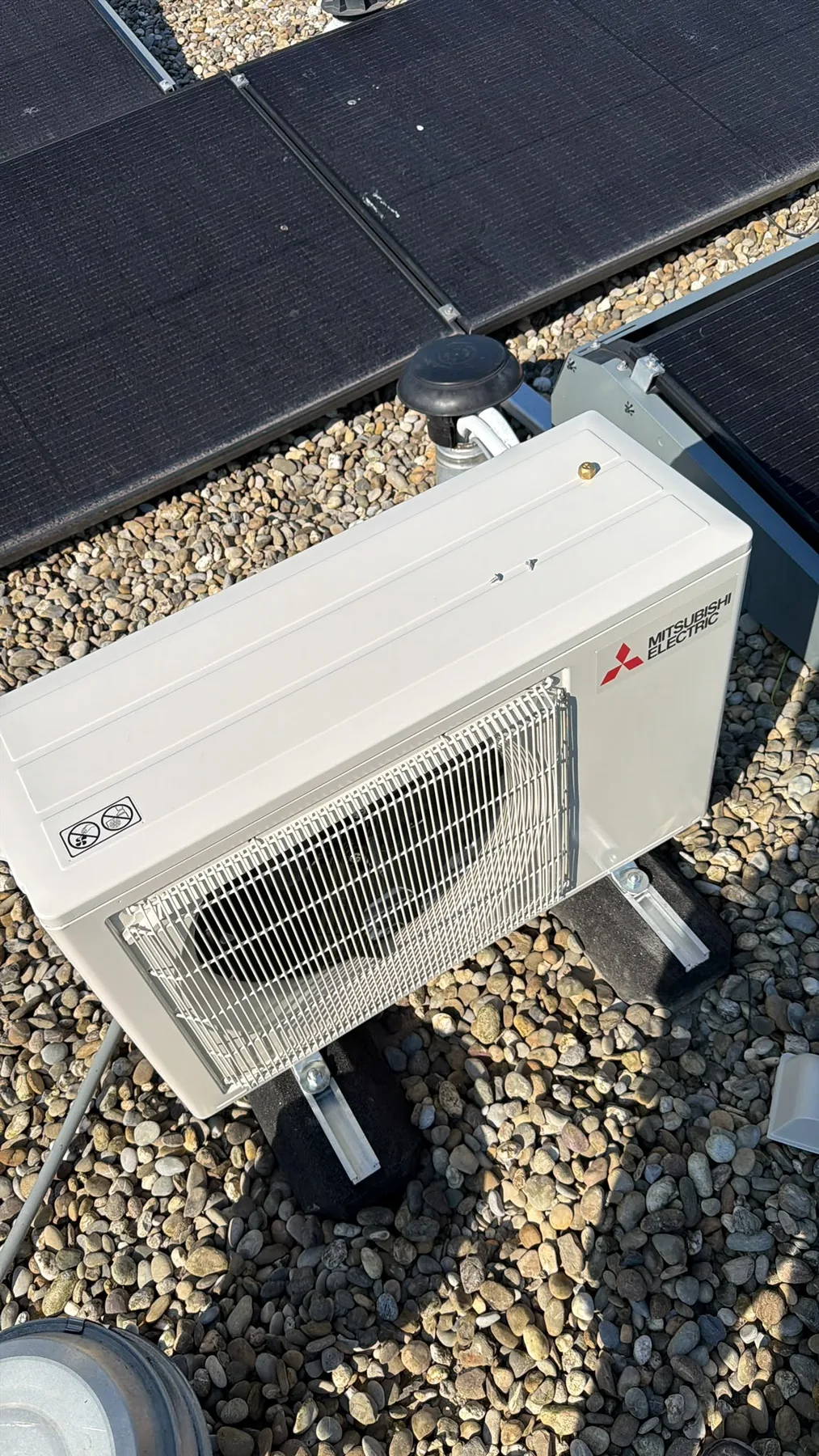 Mitsubishi Electric buitenunit op een plat dak naast zonnepanelen