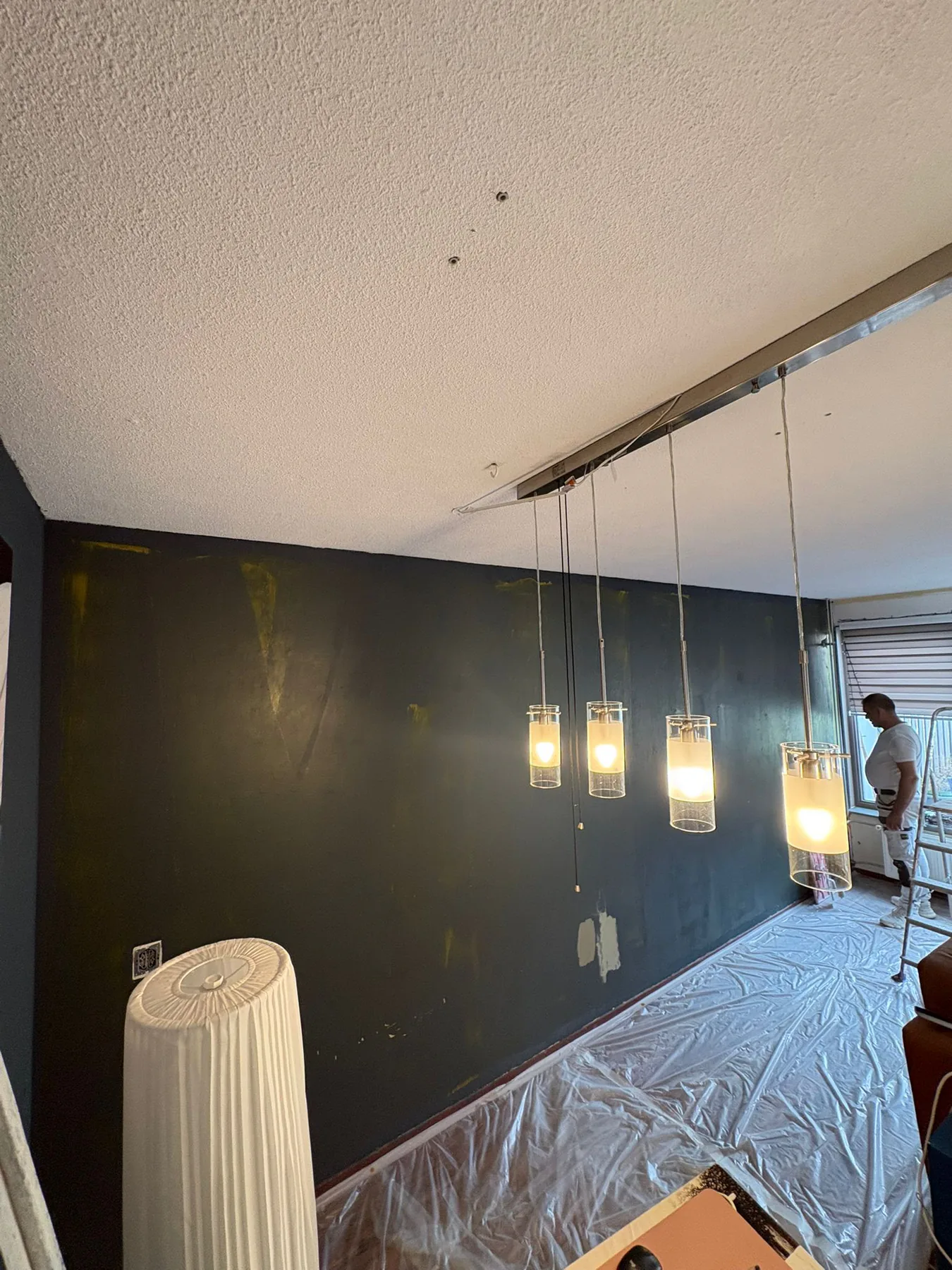 Donker afgewerkte accentwand met pendels in de woonkamer van de buurman in Almere