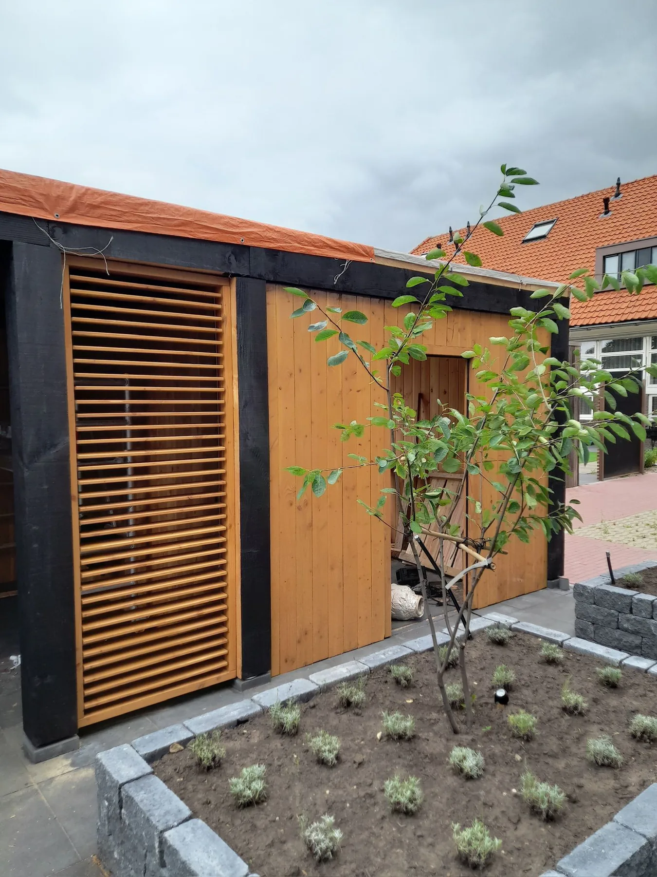 Moderne tuinberging met zwarte en houten gevelbekleding
