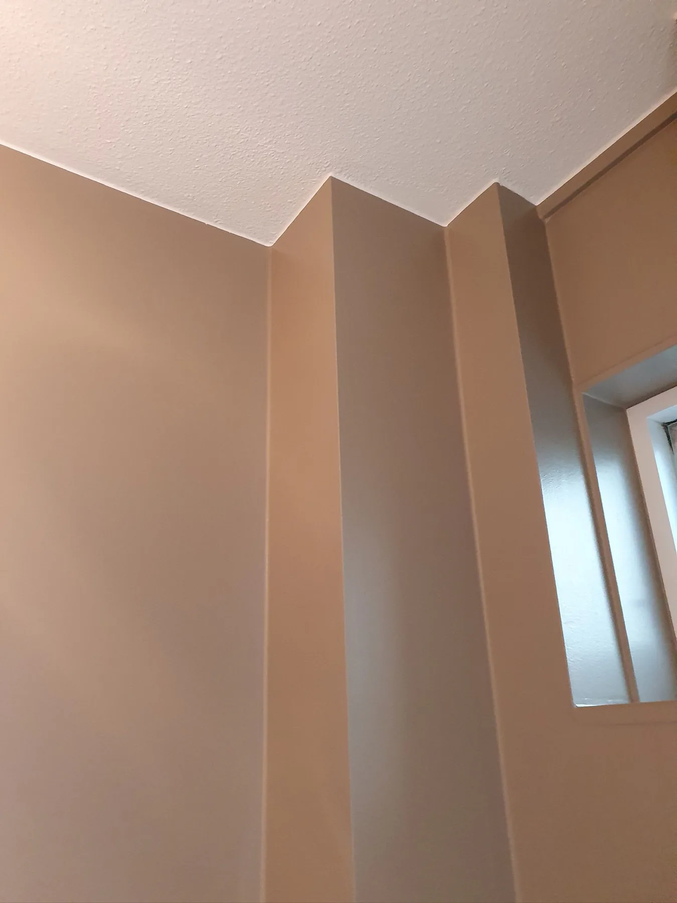 Strak gesausde taupe wanden met witte structuurplafond