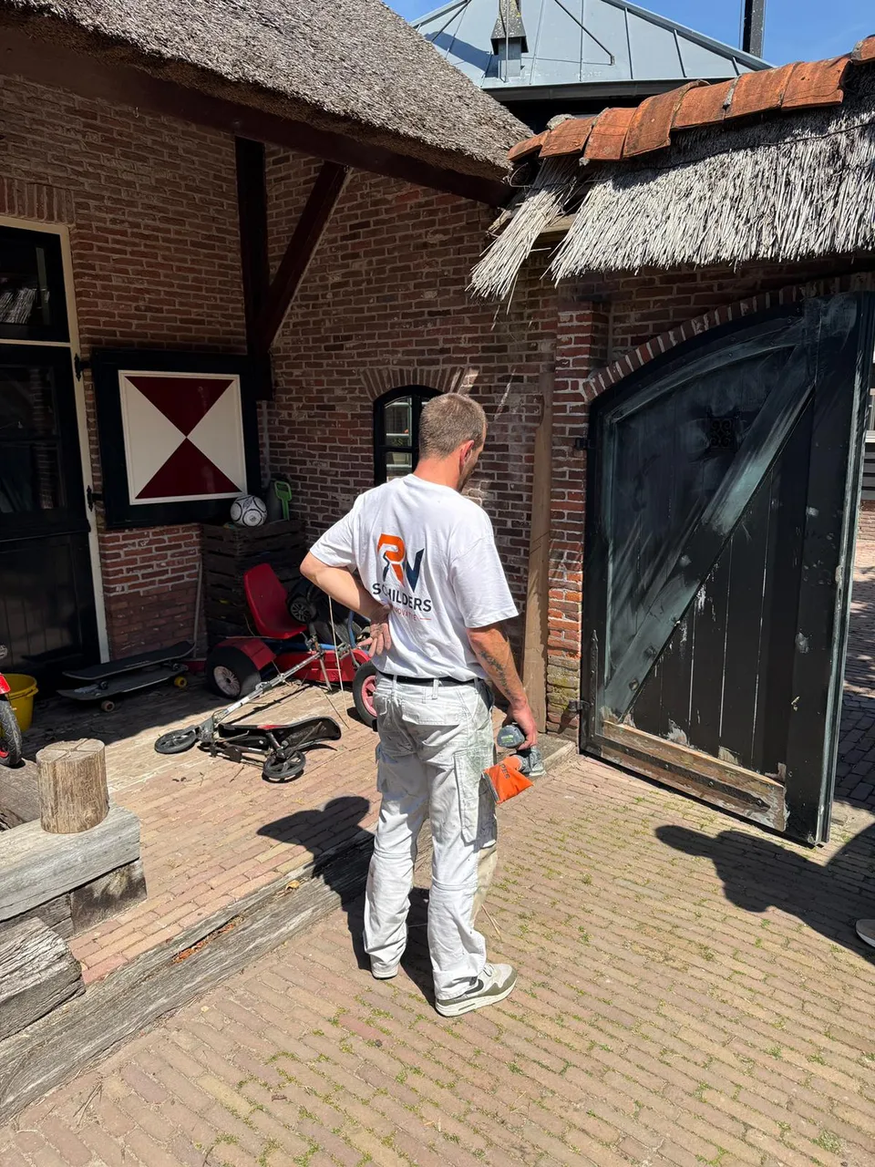 Schilder op een boerenerf bij een bakstenen boerderij met rieten schuur